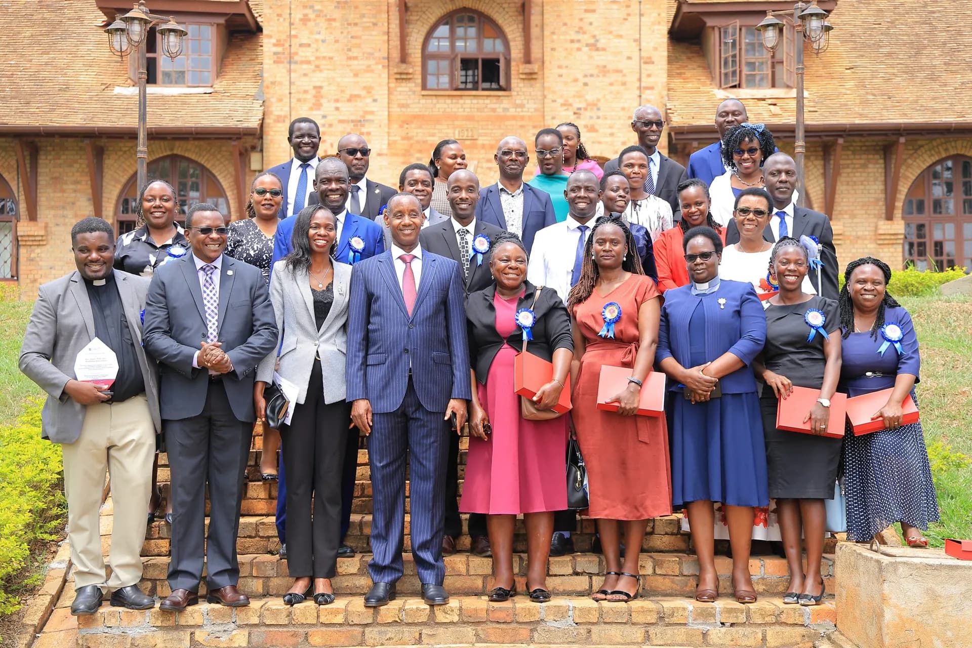 Uganda Christian University staff in front of a historic campus building