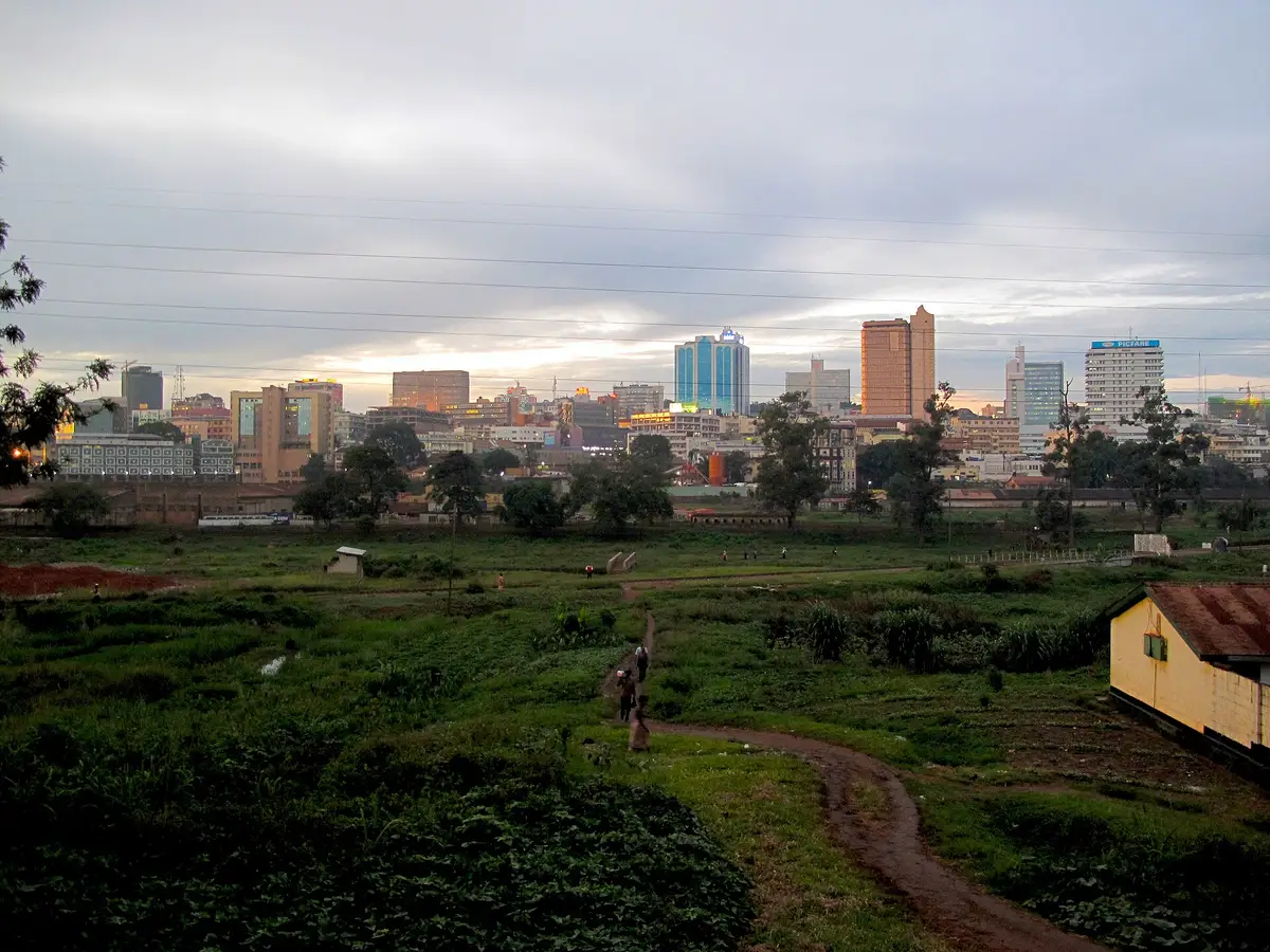 Kampala's skyline at dusk across open ground