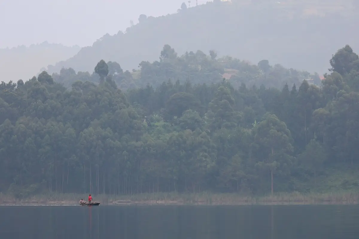 A canoe on misty Lake Bunyonyi below forested hills