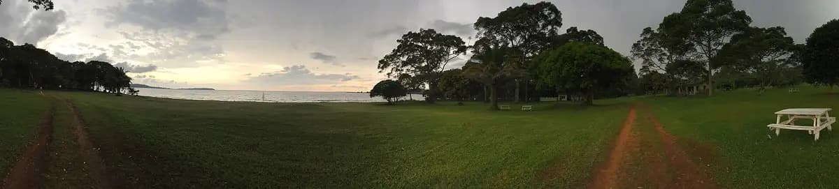 Lawn and trees at a lakeside lodge on the Ssese Islands